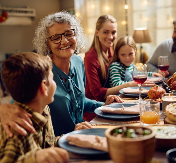 Three generations of a family laughing together around the Thanksgiving table